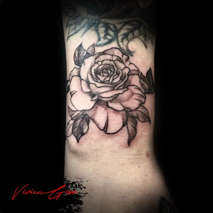 realistic tattoo of a rose tattooed on the woman's arm 