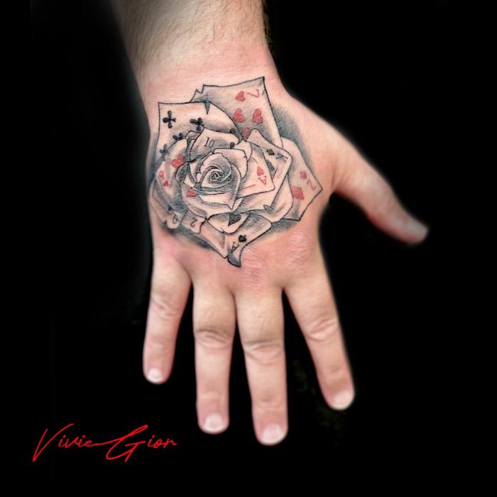  realistic tattoo of a rose on hand made from plating cards in realism