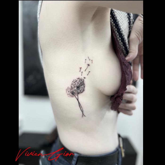 realistic tattoo of a flower giving of its leaves on womans side 