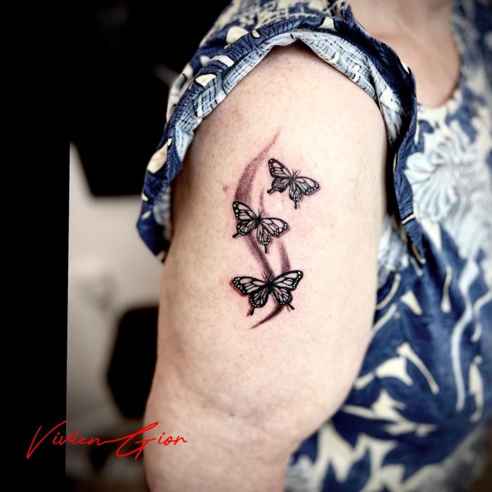 realistic tattoo of butterflies flying across the arm of women in realism