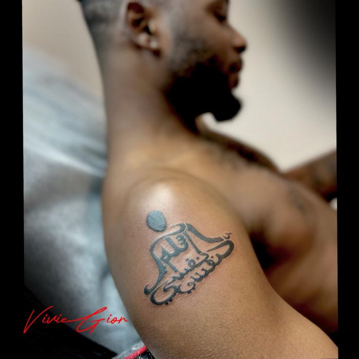 tattoo of a stickman praying costisting of hindi letters on shoulder 